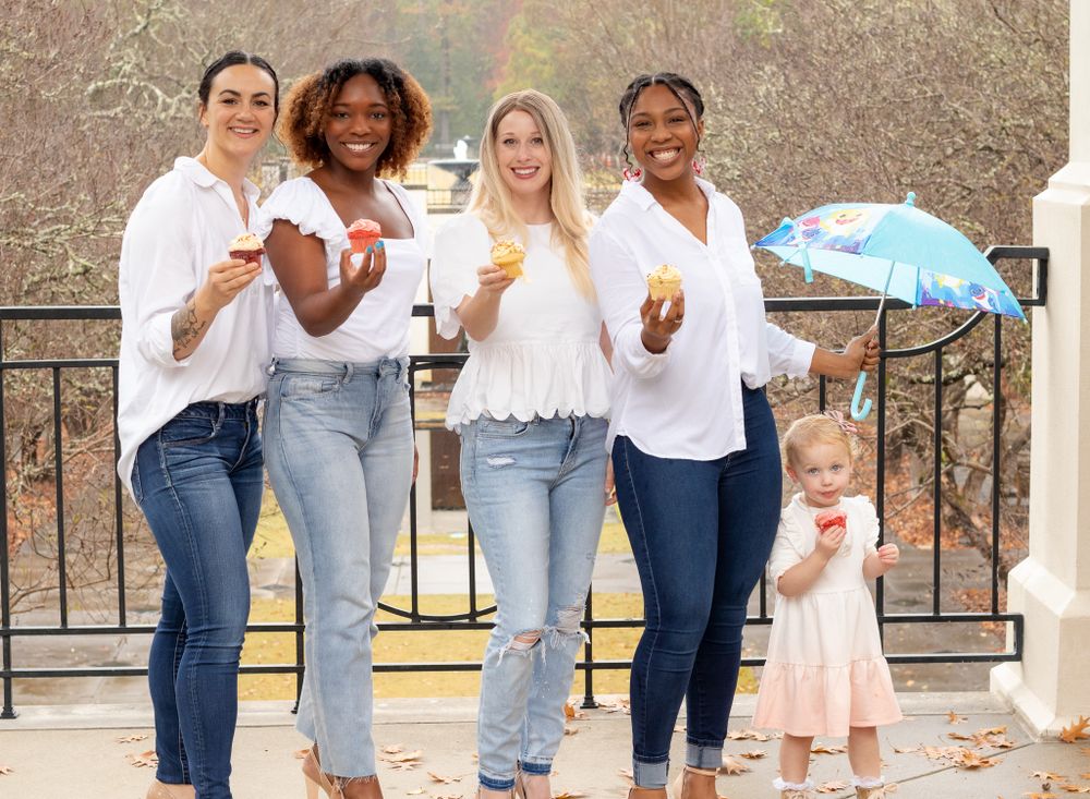 Group of friends in casual white tops and jeans posing together outdoors.