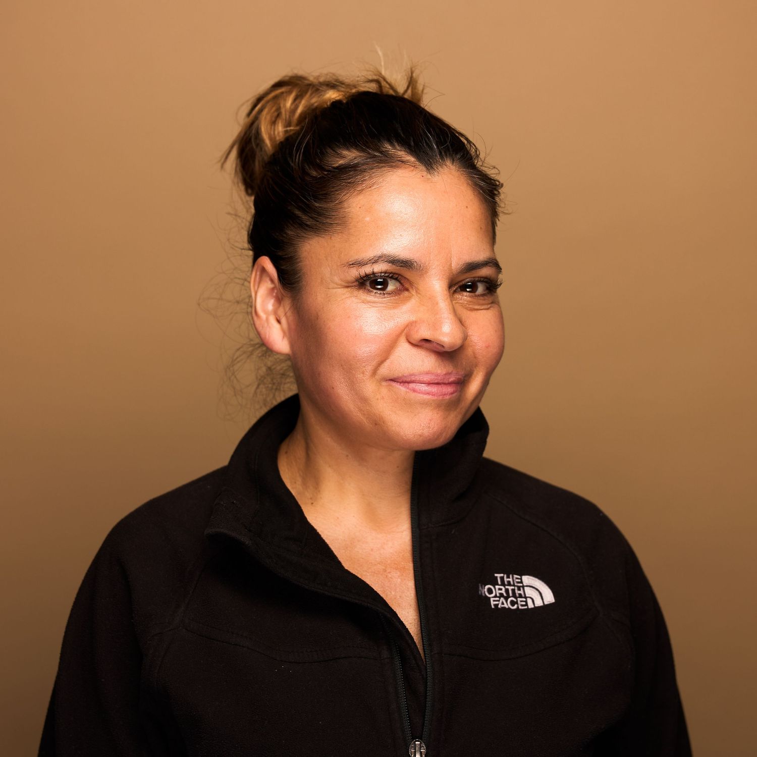 Professional portrait of person wearing North Face jacket with hair pulled back.