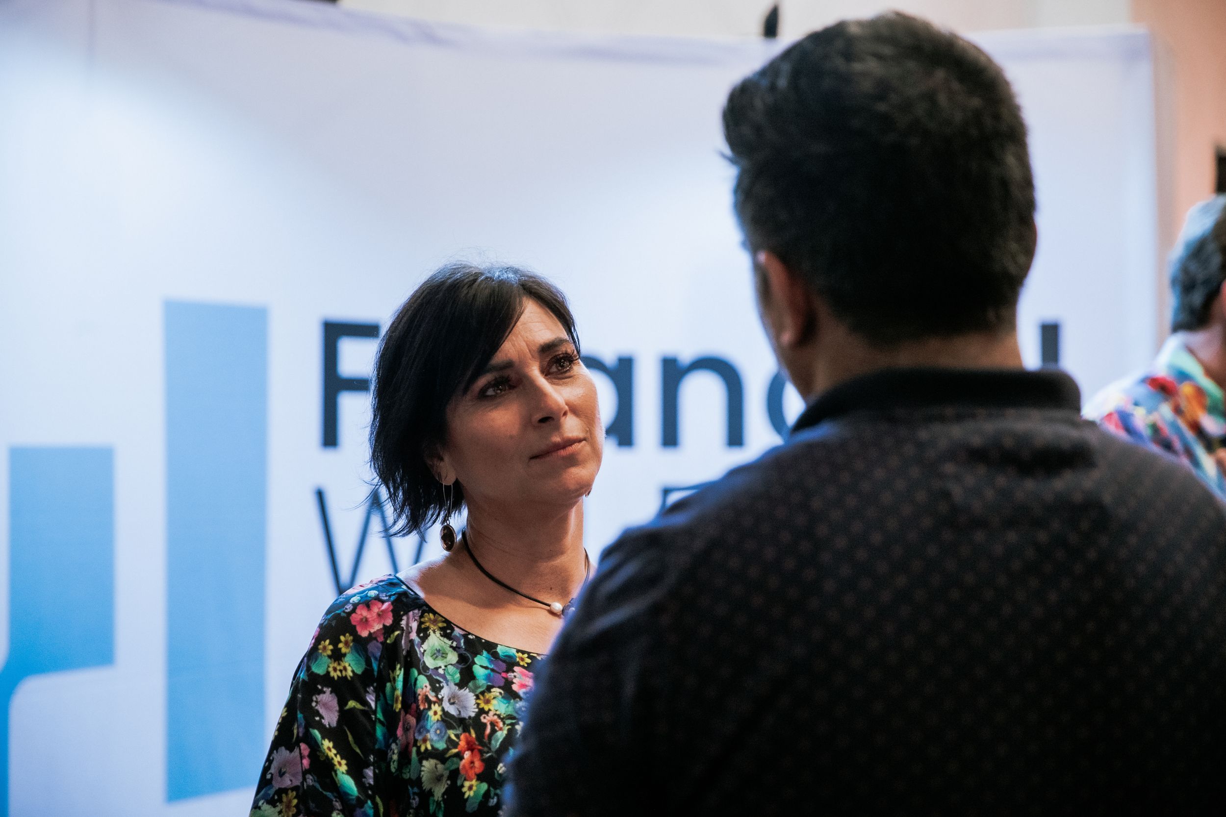 Two people engaged in conversation in an office or professional setting.