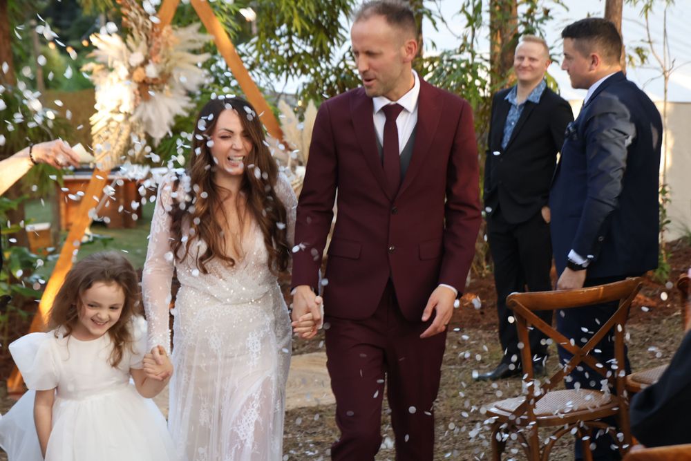 Wedding recessional with confetti being thrown in a forest setting with geometric arch and dried flowers.