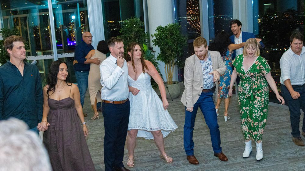 Wedding guests performing synchronized dance moves in a modern venue setting.