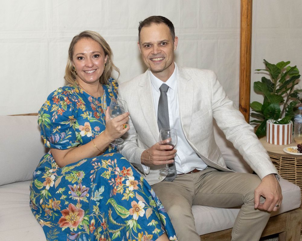 Couple in formal attire posing together at indoor celebration.