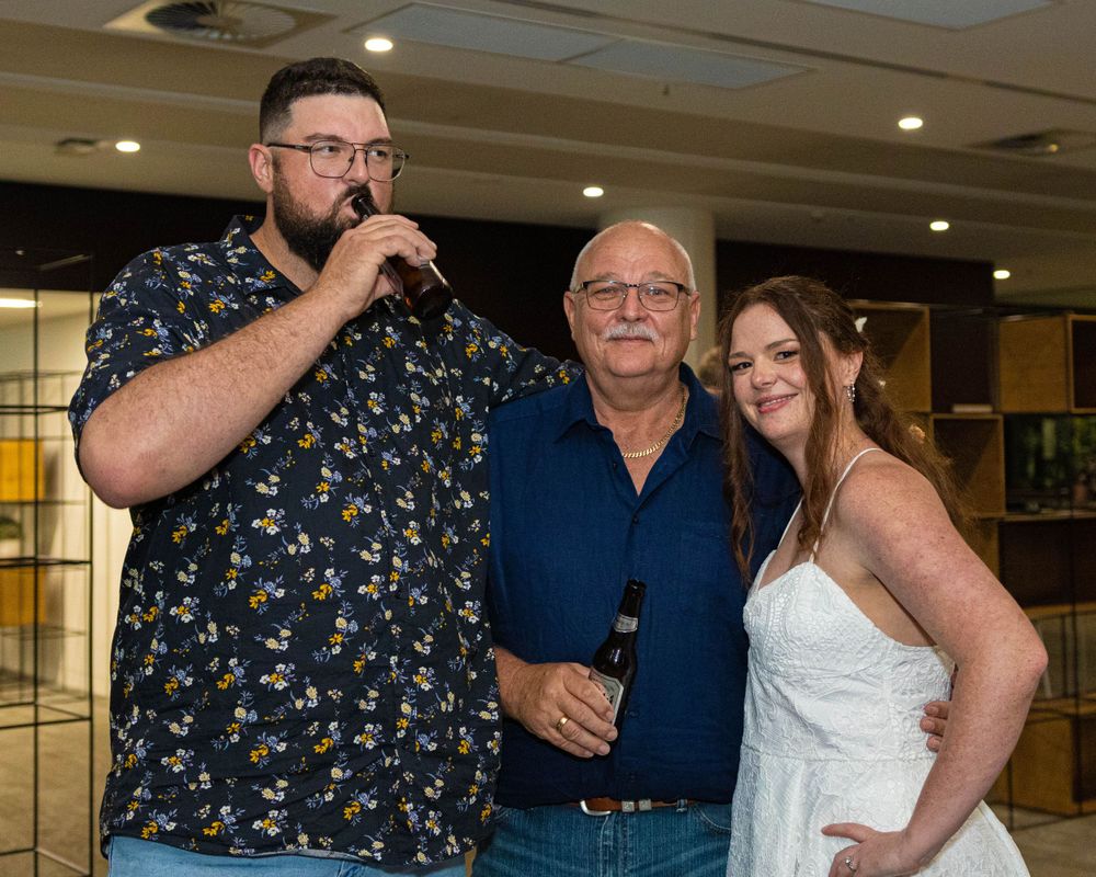 Three people posing together at an indoor celebration event.