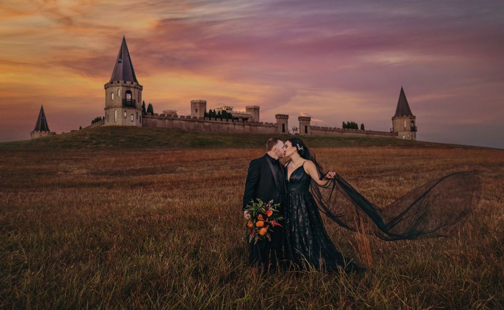 Bride and Groom kissing in front of the Lexington Castle in Kentucky after getting married, both wearing black to celebrate Halloween month