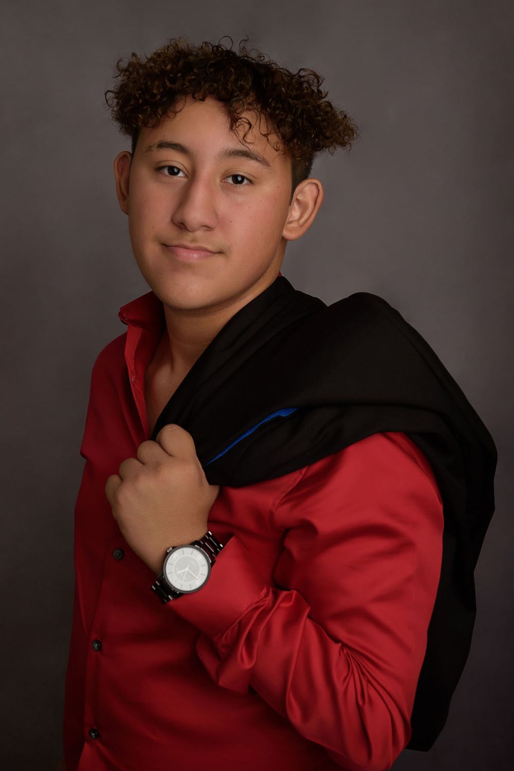 Portrait of someone in a red shirt and black jacket holding a dark coat.