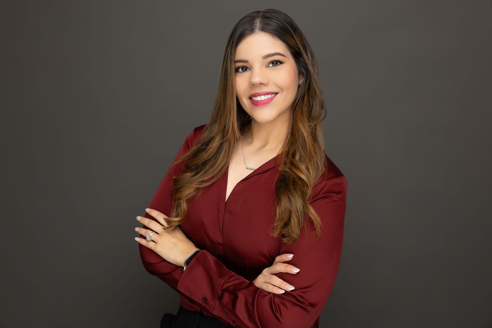 Business portrait featuring burgundy top and styled hair against dark backdrop.