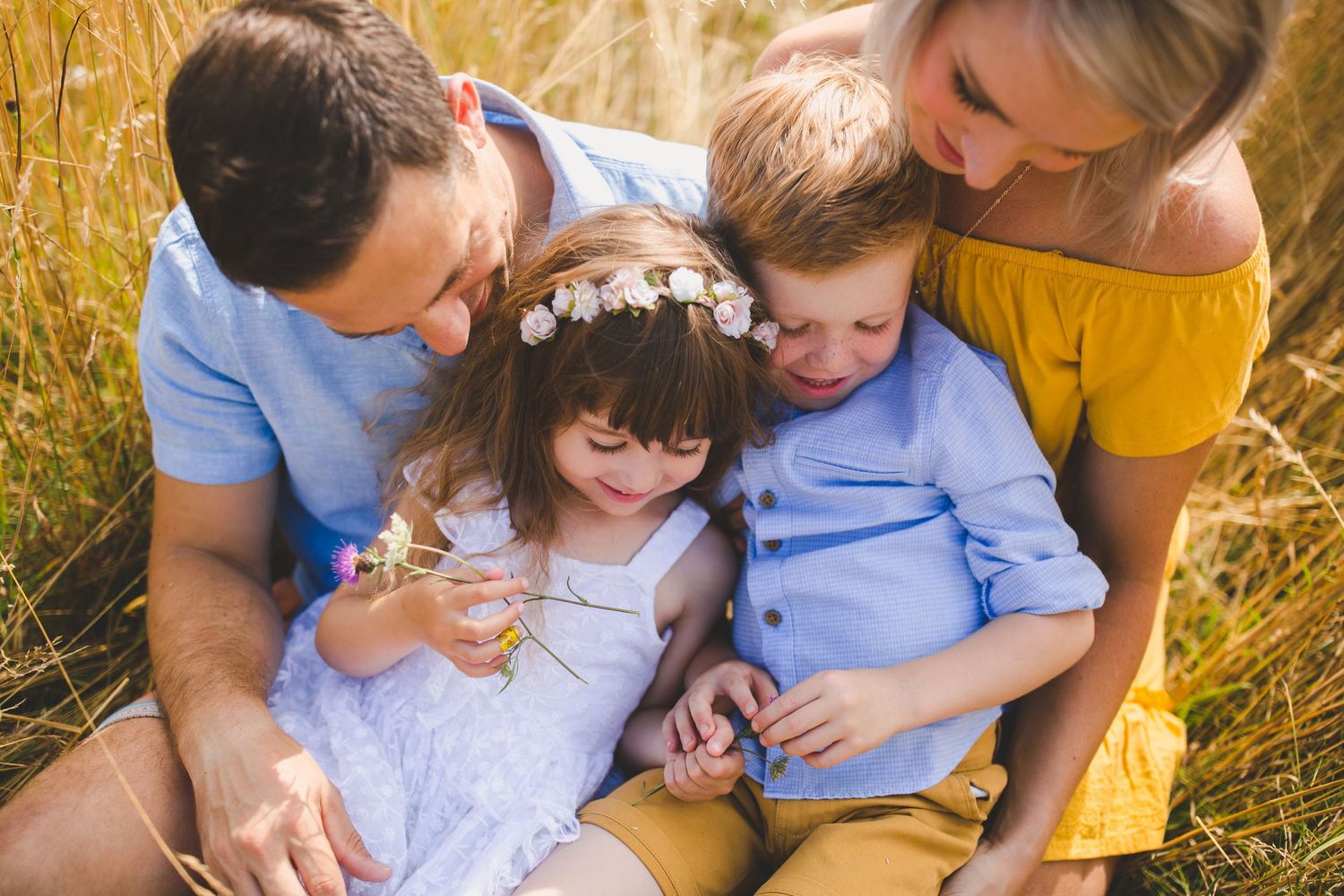 Family enjoying tender moments together in golden wheat field at sunset.