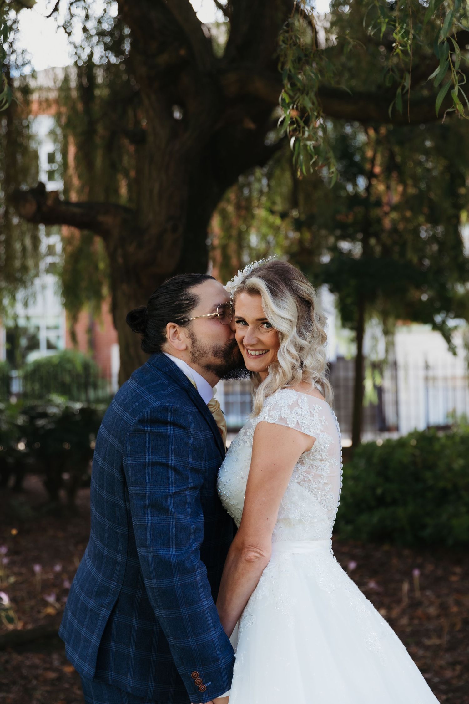 Romantic outdoor wedding portraits with couple embracing under trees.
