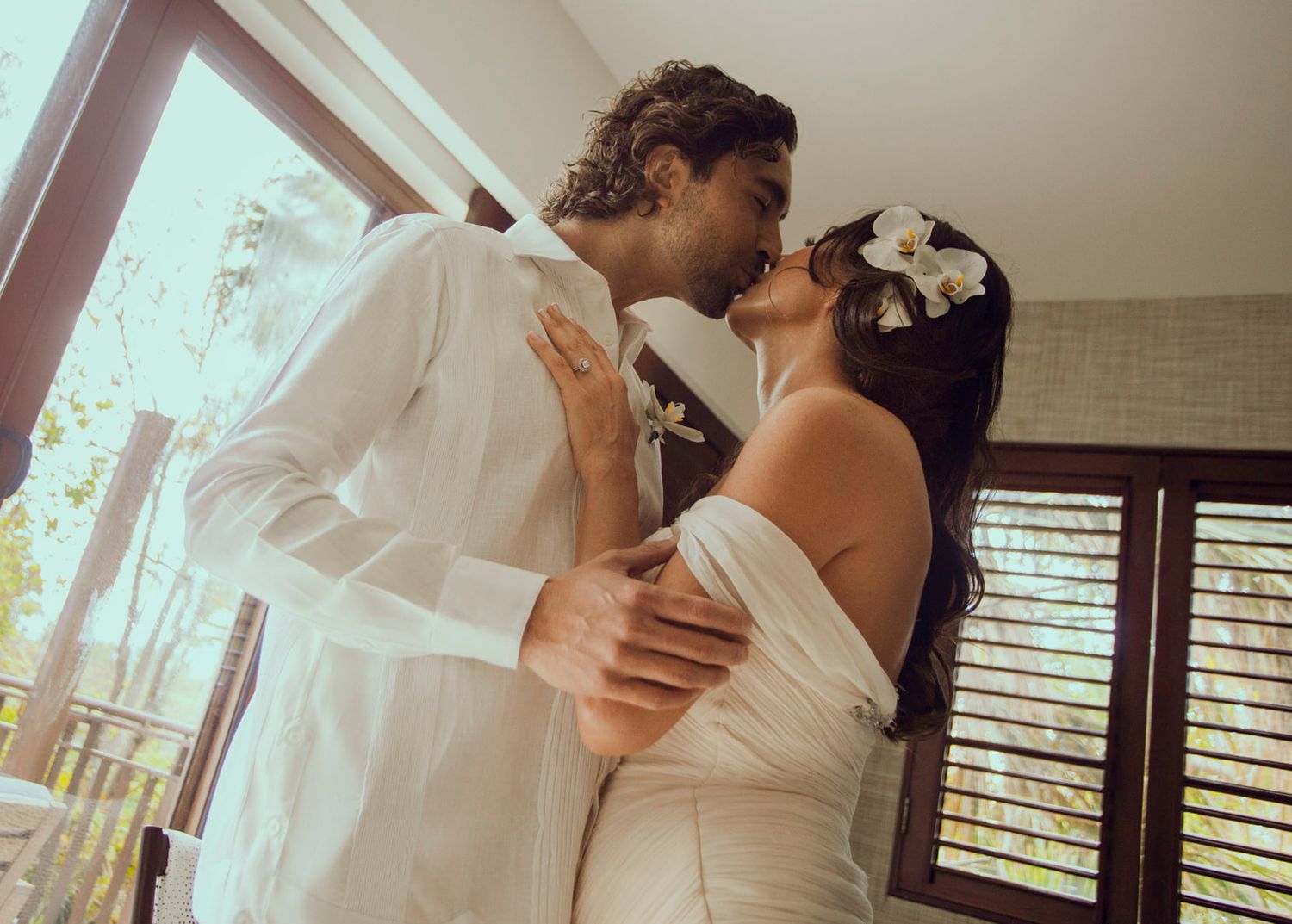 Intimate wedding moment captured in natural light by a window.