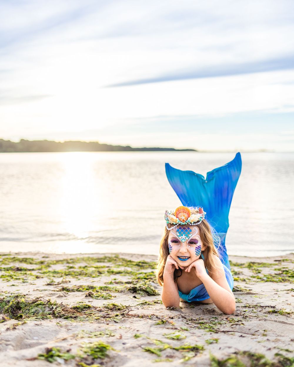 Magical mermaid pose on mossy beach during golden hour.