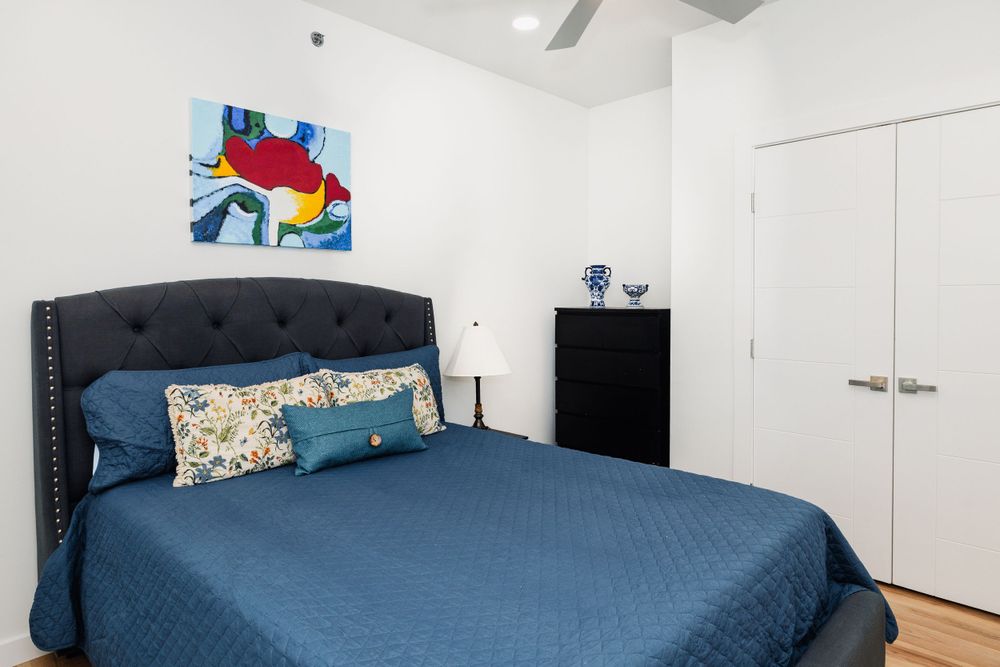 Modern bedroom with navy bedding, tufted headboard and colorful abstract wall art.