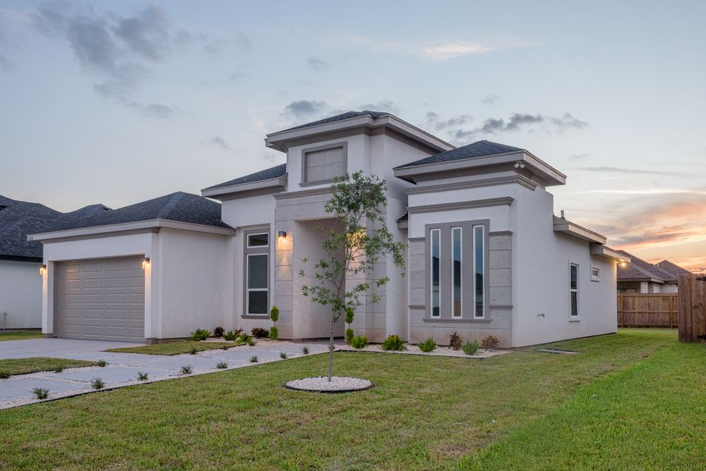 Modern white stucco house with contemporary architecture and manicured lawn at dusk.