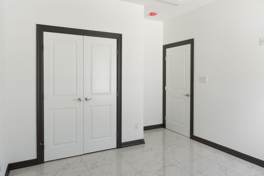 Hallway with glossy floor, white double doors and dark trim details.