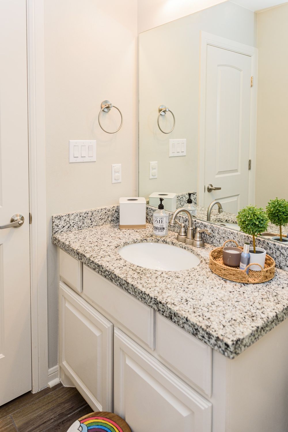 Bathroom vanity with granite countertop, white cabinets and decorative accessories.