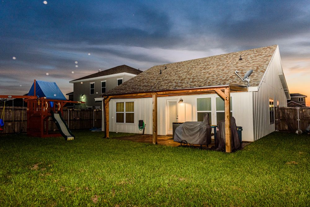 Backyard view of house exterior at dusk with playground equipment visible in the yard.