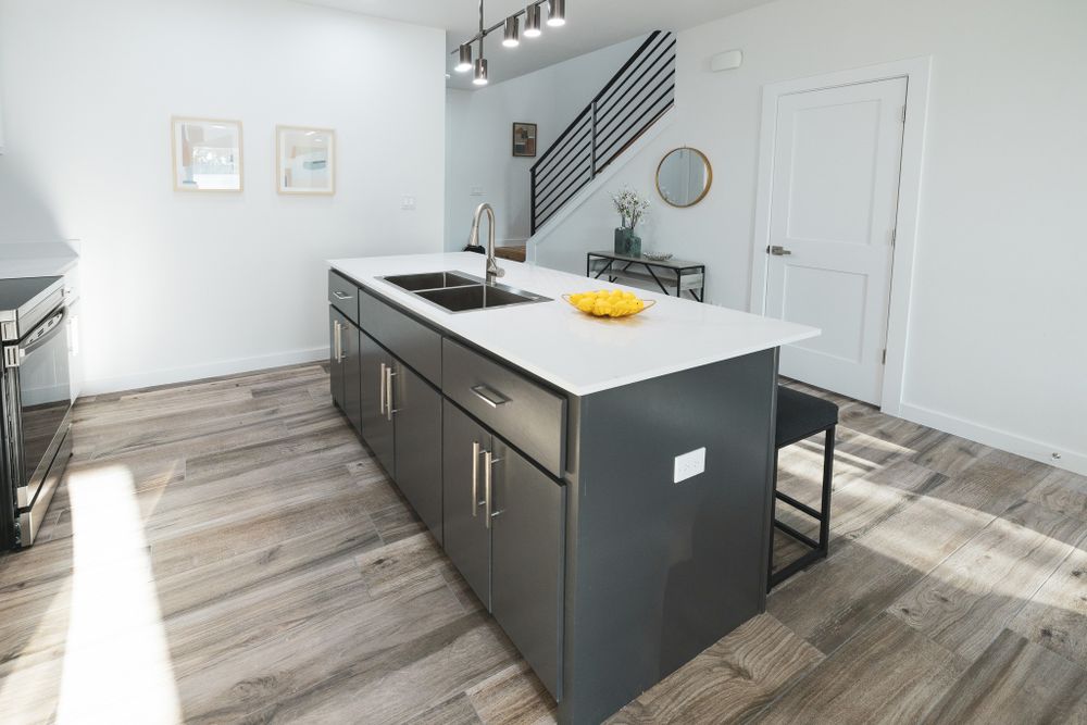 Sleek kitchen island with dark gray base cabinets and white countertop in sunlit space.