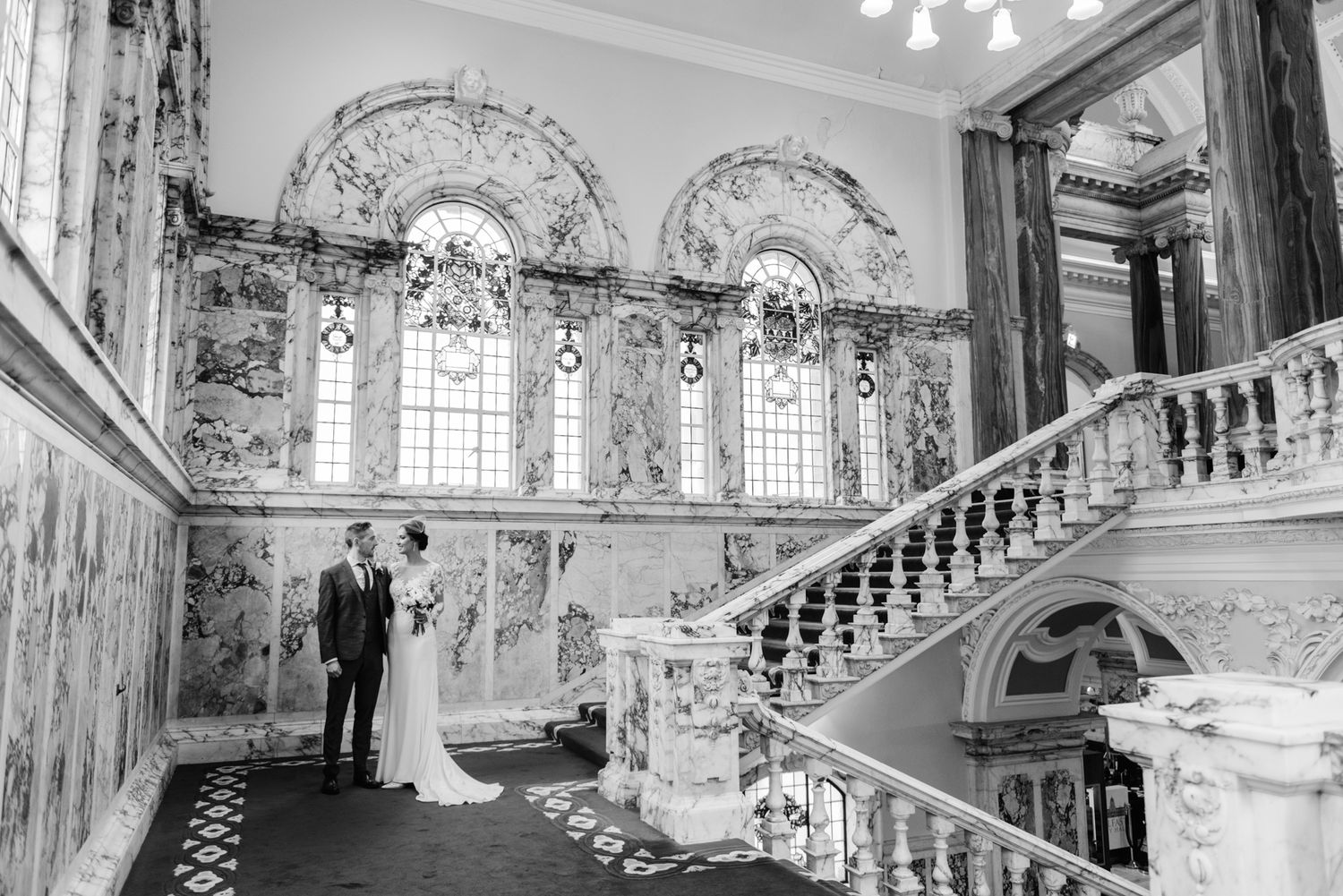 Couple in wedding attire facing each other in a palace