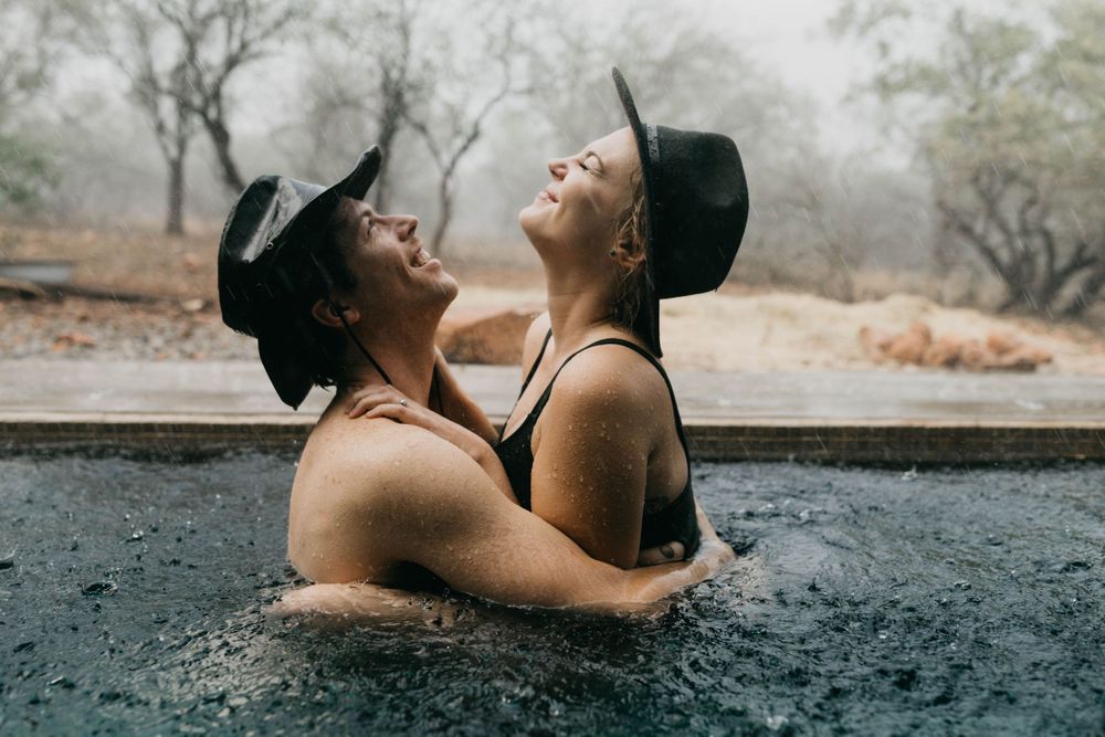 A romantic couple shares an intimate moment in a pool during sunset.