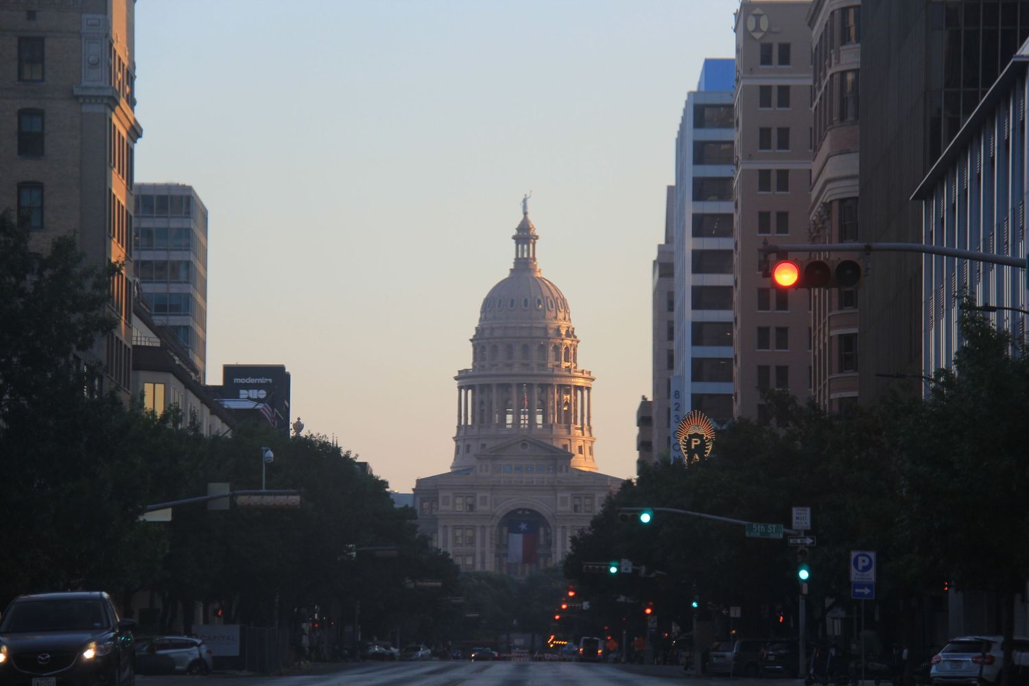 Texas State Capitol building viewed through downtown Austin streets at dawn.