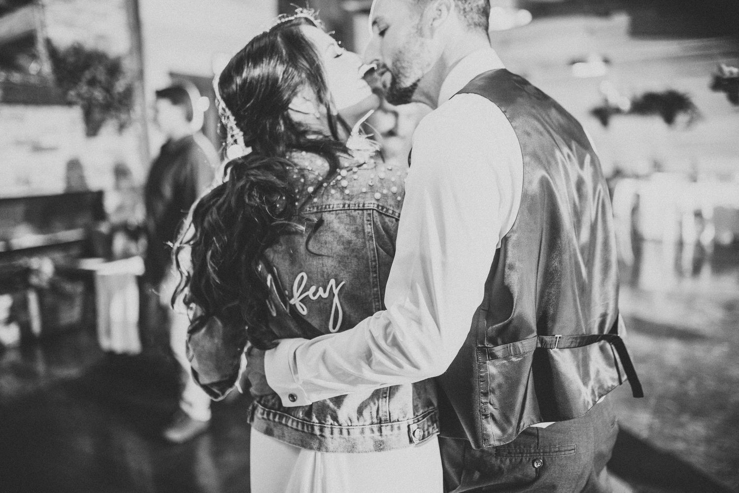 Black and white photo of couple in vintage-inspired wedding attire sharing intimate moment.