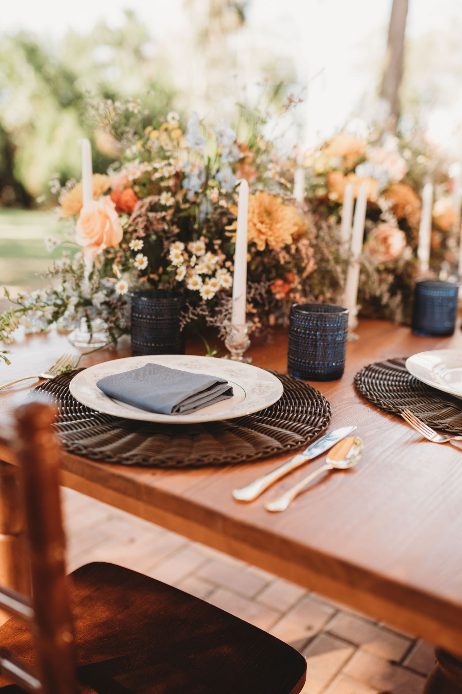 Rustic wedding table setting with peach floral centerpiece and blue glass accents.