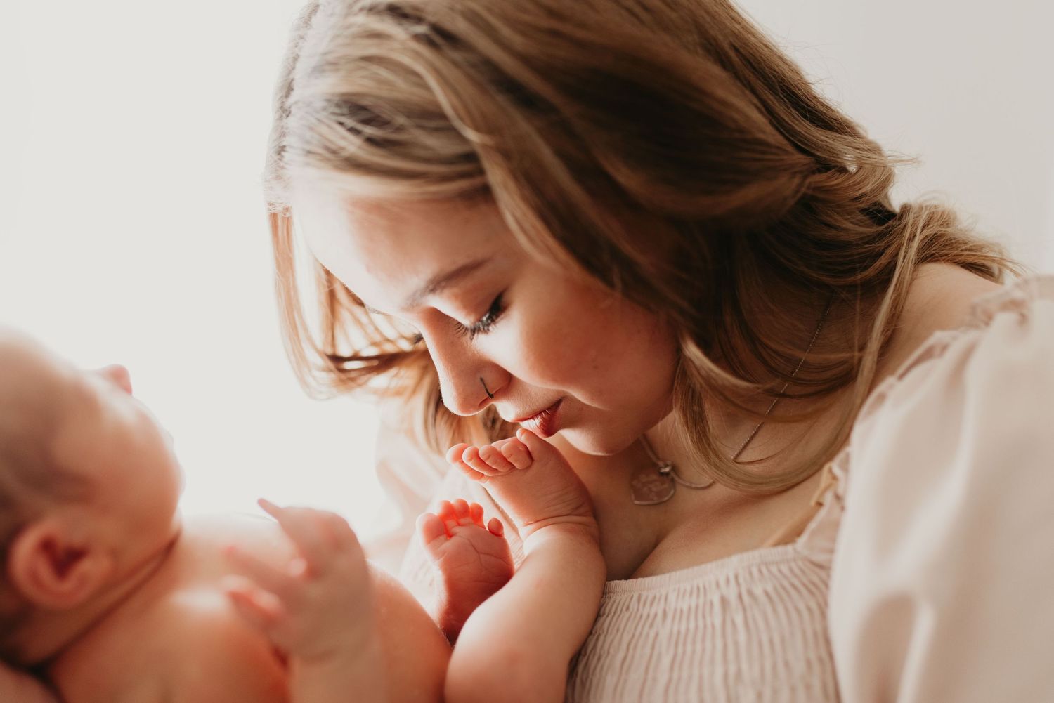 Tender moments captured between parents and newborn in soft natural light.