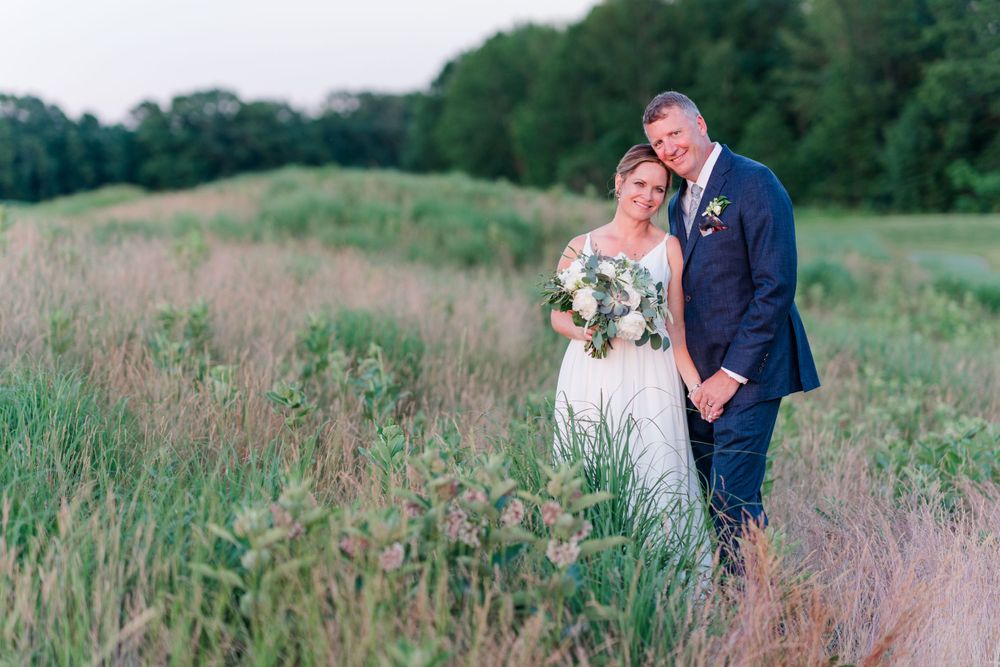 Elegant wedding portrait in a natural meadow setting during golden hour.