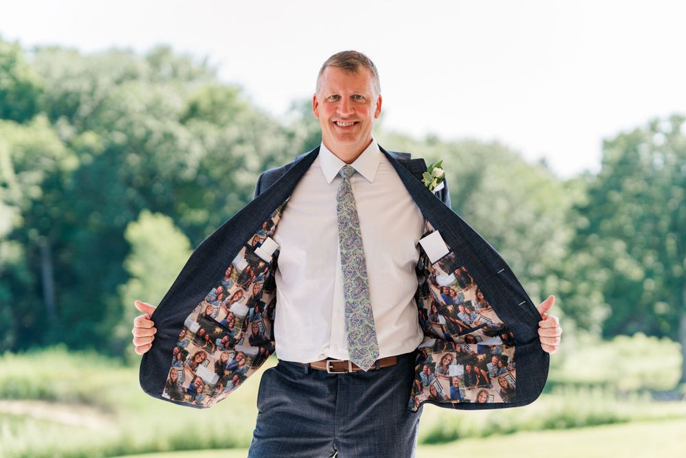 A person shows off the floral lining of their suit jacket while posing outdoors.
