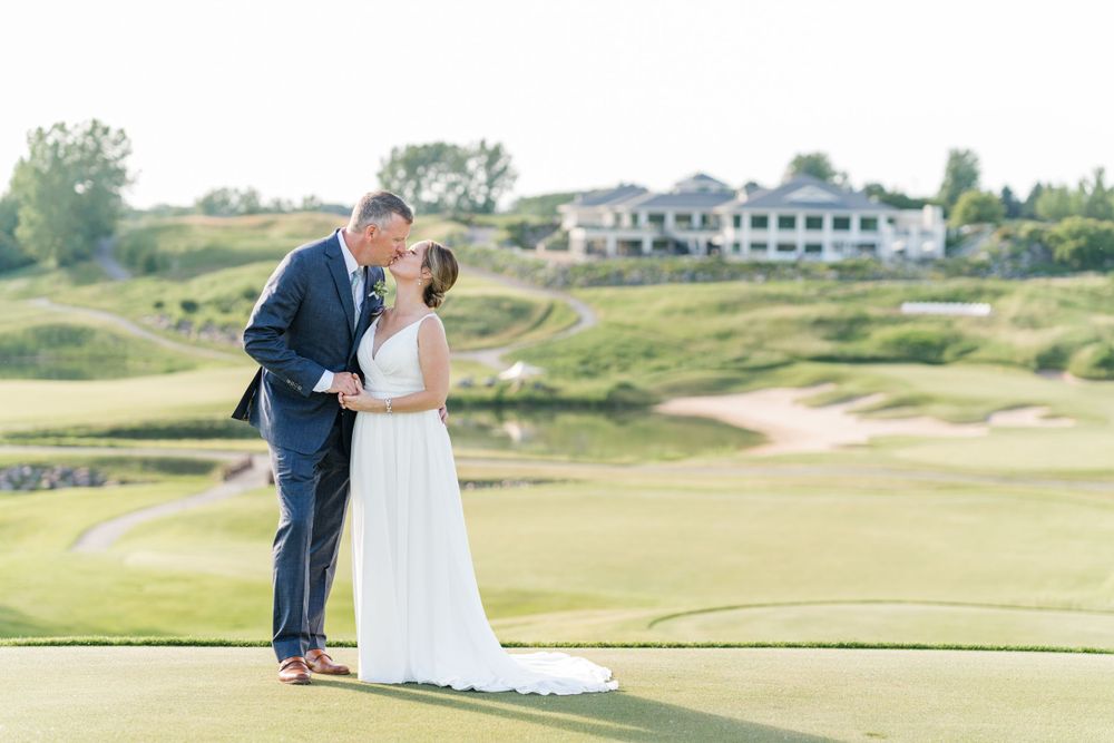 Romantic wedding photo on a manicured golf course with elegant clubhouse in background.