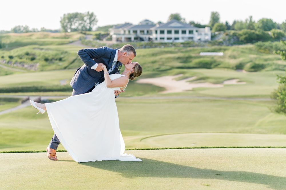 Playful wedding dance dip pose on pristine golf course greens.