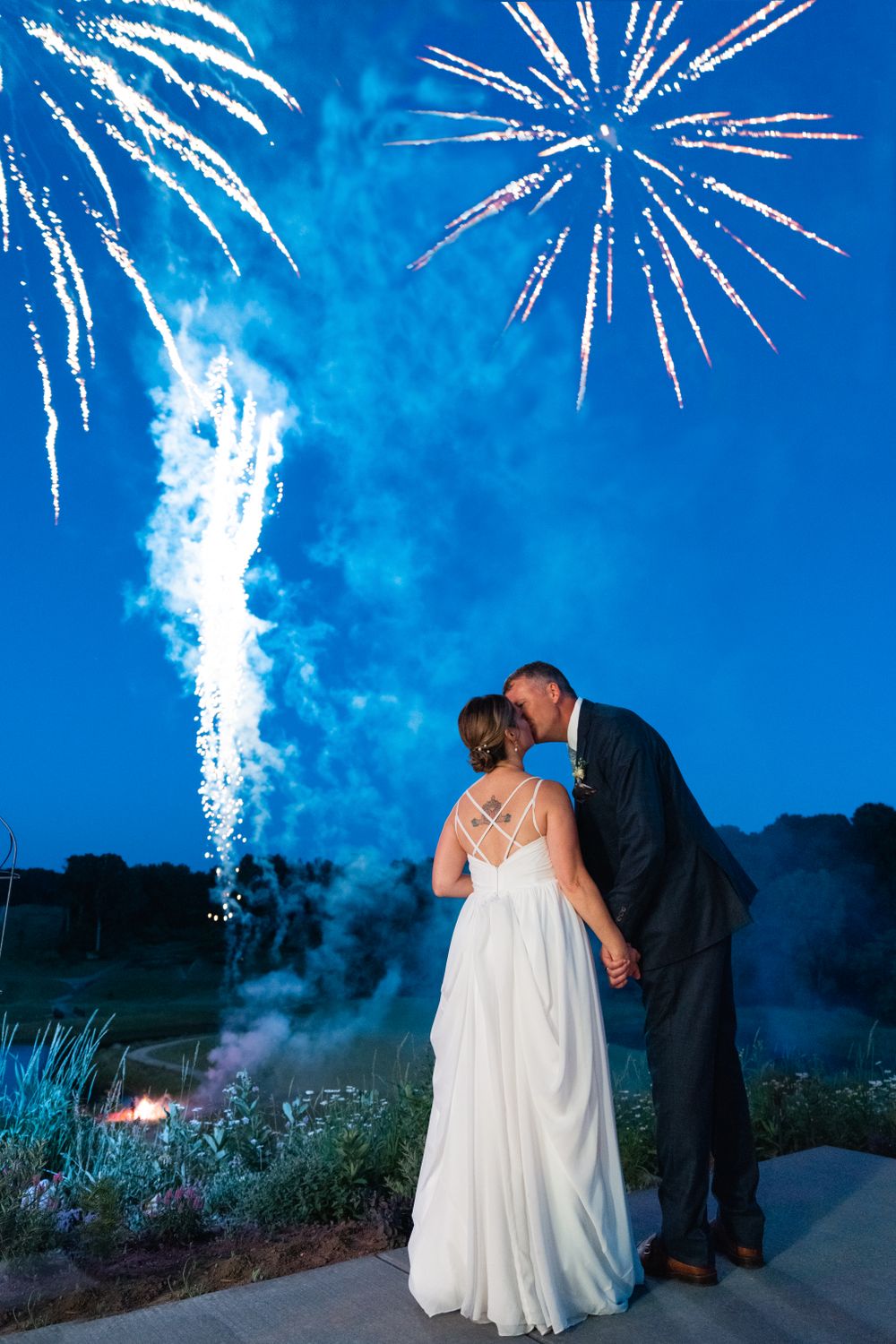 A romantic moment under spectacular fireworks display with a couple on an outdoor patio.