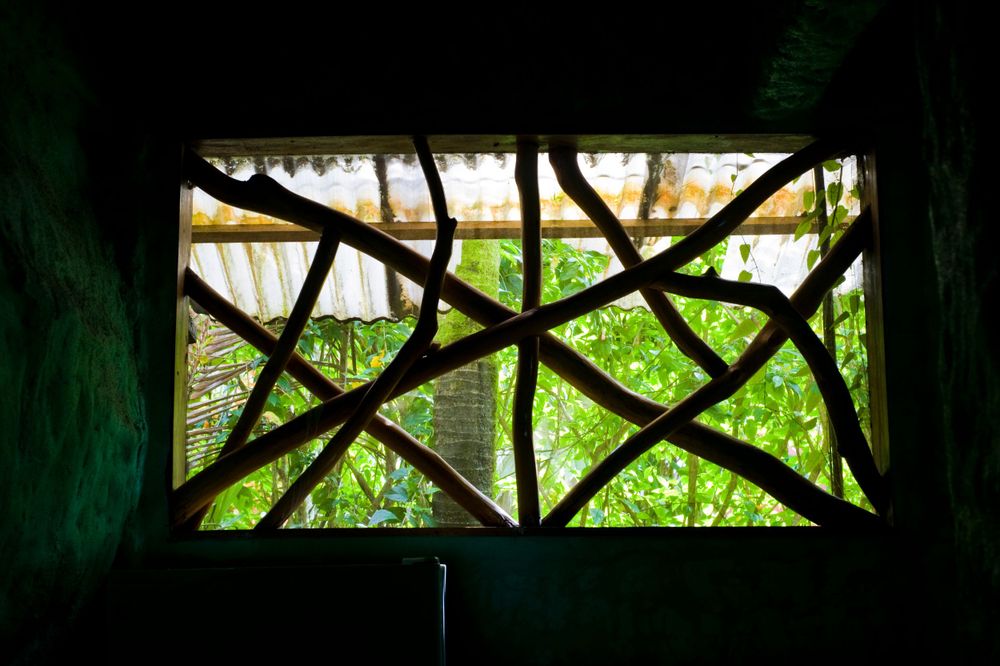 Dark silhouette of a porch railing against bright green foliage in the background.