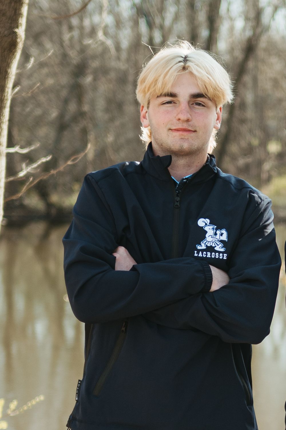 Series of casual poses by a water's edge wearing a dark jacket on a winter day.
