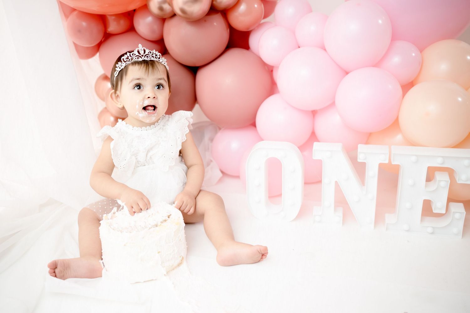 Pink balloon arch and decorative elements set up for a baby's first year photo session.