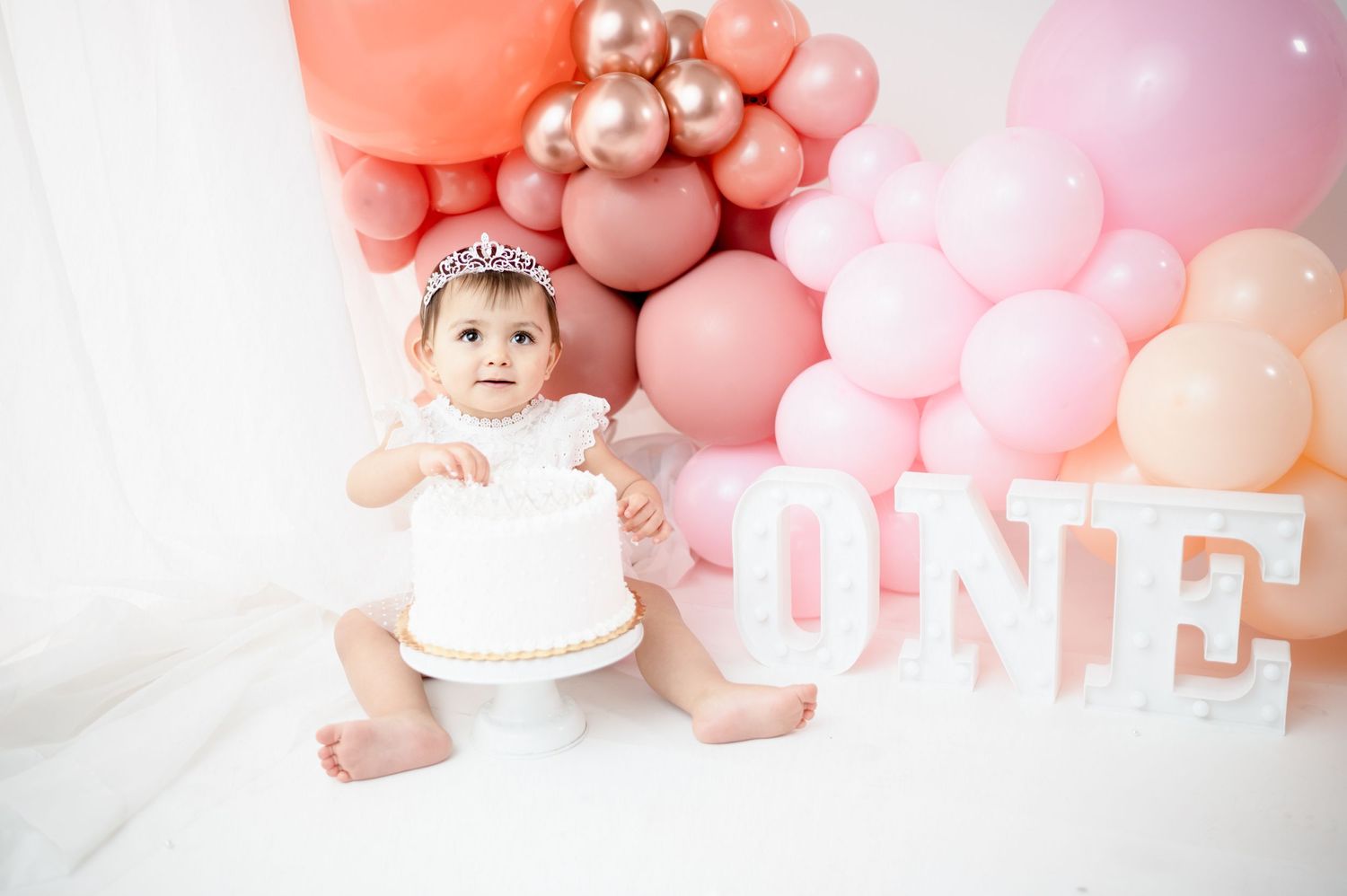 Pink balloon display with white lettering arranged for baby photography session.