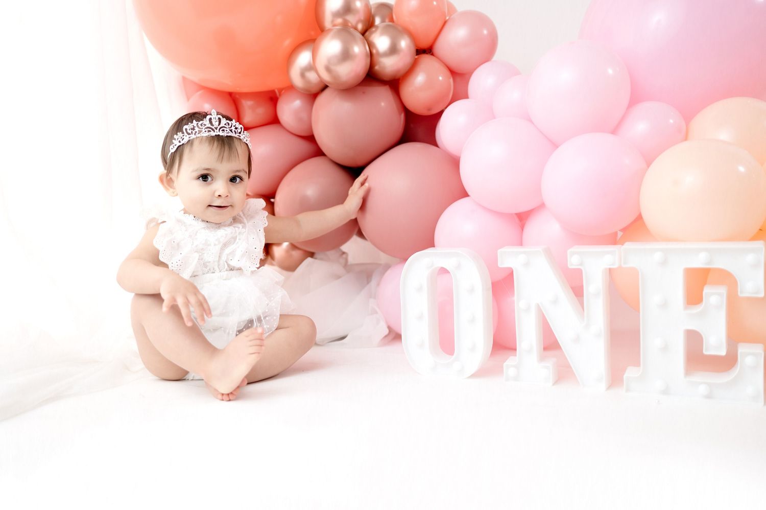 Pink balloon decorations and props arranged for a baby photography session.