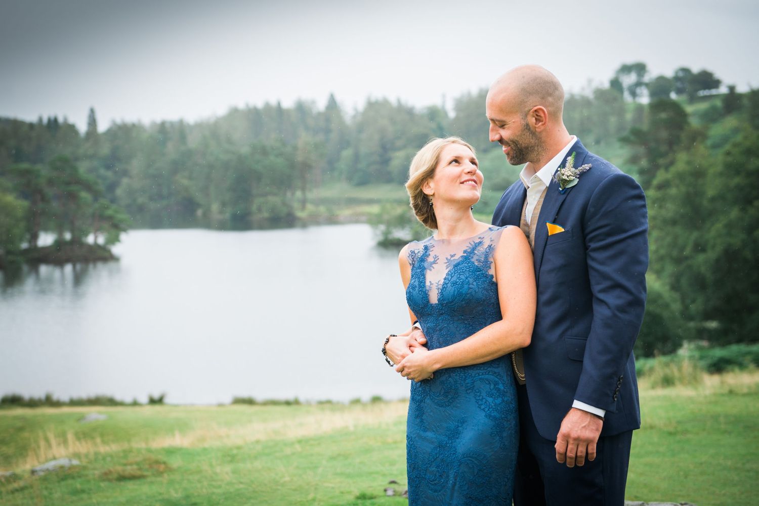 Couple in wedding attire gaze at each other in front of the view at Tarn How's