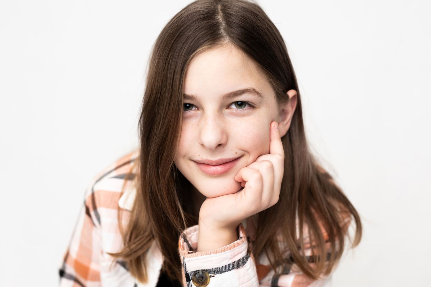 Portrait of a person resting their chin on hand while smiling at camera.