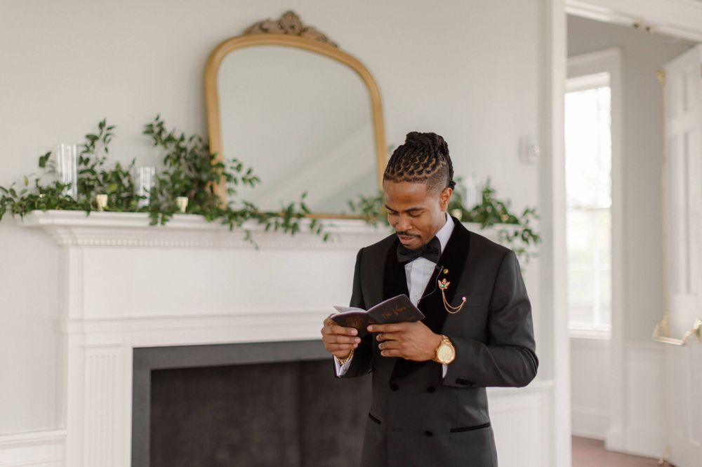 A formal wedding detail shot showing someone reading a document in a classic interior.