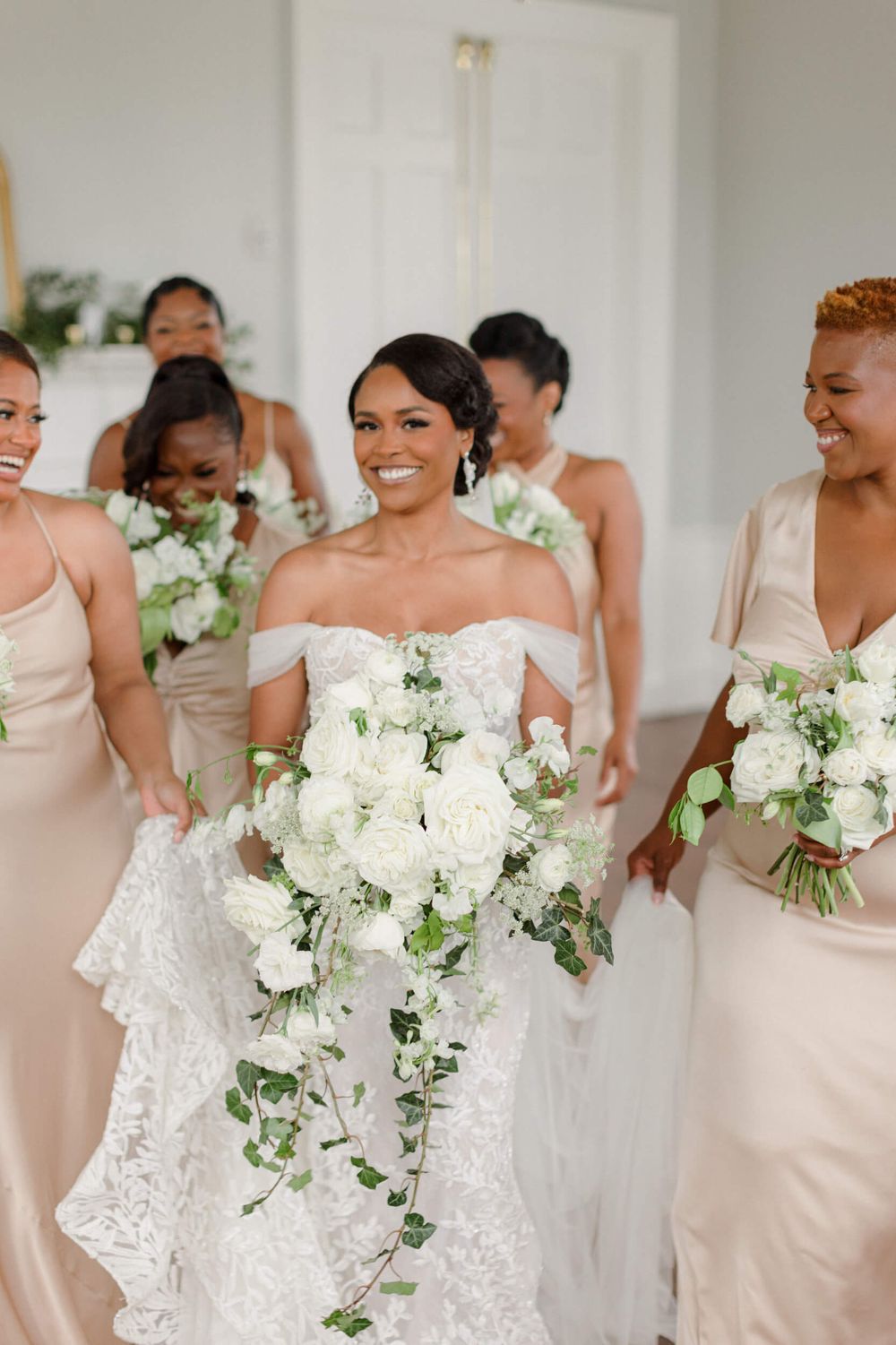 A wedding party featuring bridesmaids in blush dresses holding elegant white floral bouquets.