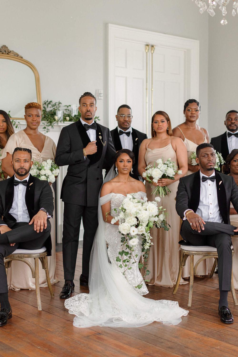 Formal wedding party portrait with members in black tuxedos and champagne bridesmaid dresses.