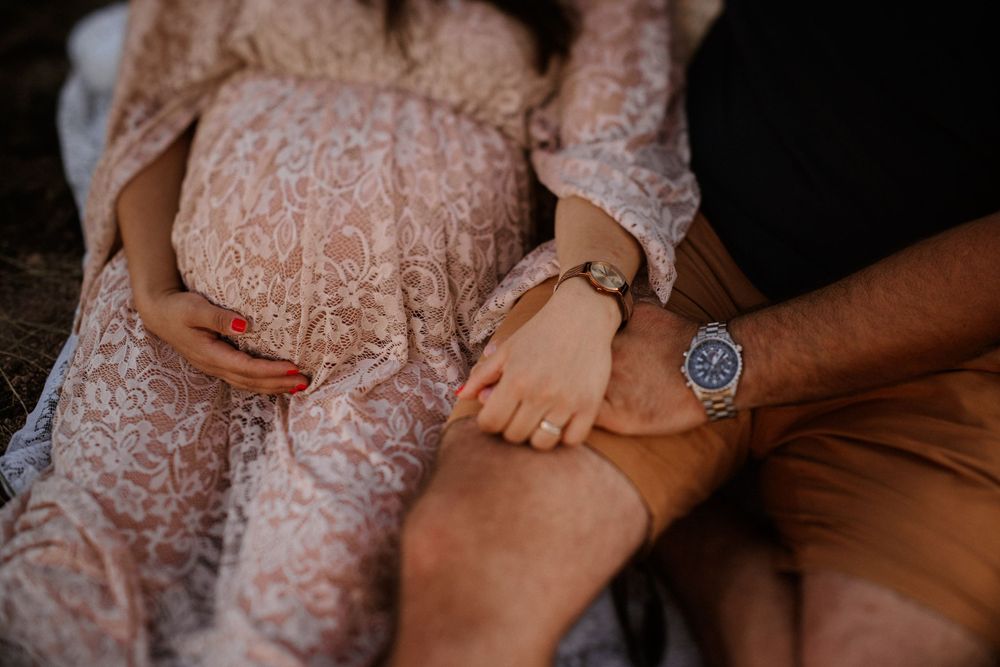 Close up of hands resting on lap wearing lace dress and casual attire.