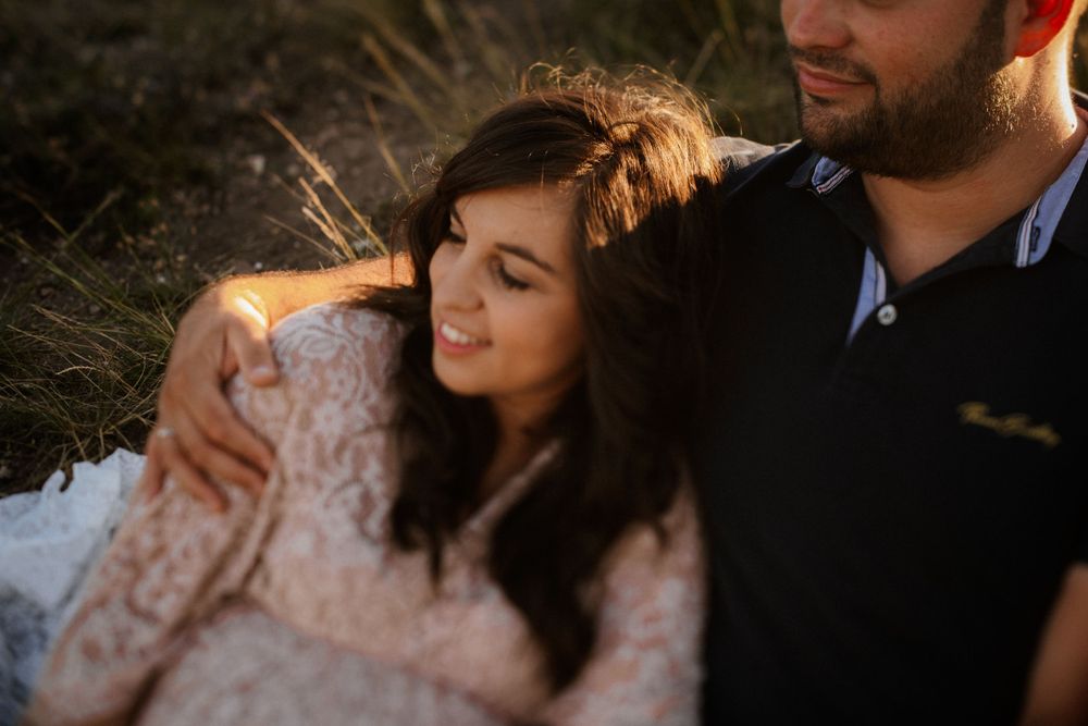 Intimate moment captured in warm sunlight with lace dress detail.