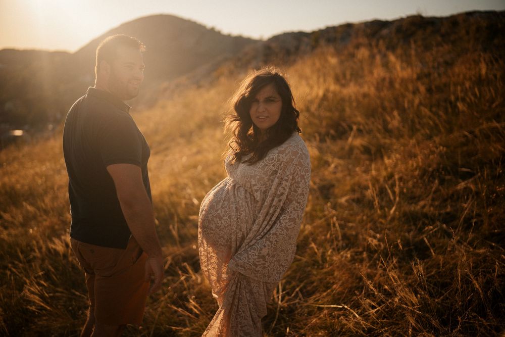 Golden hour maternity photoshoot in natural setting with warm backlight.