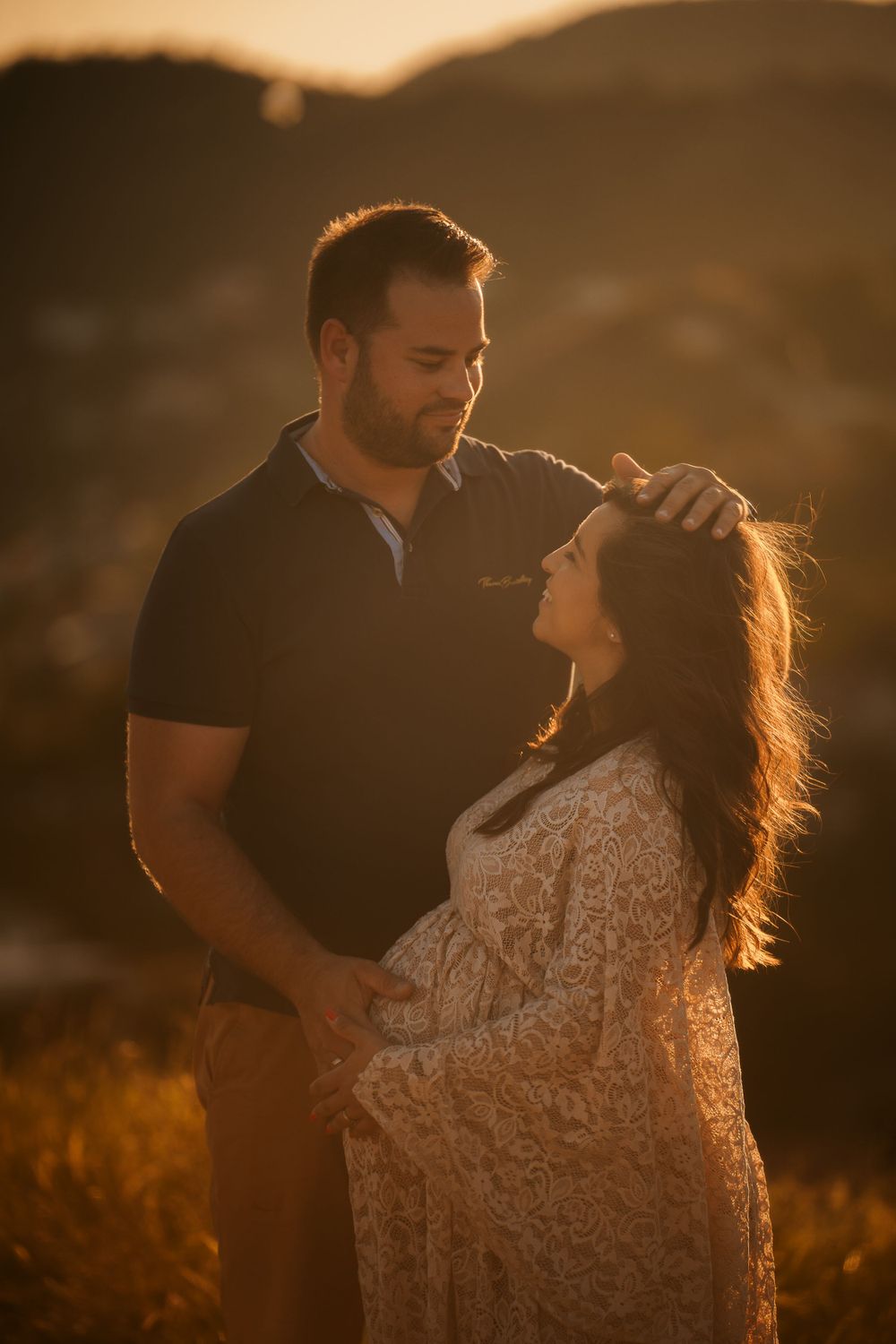 A couple shares an intimate moment at golden hour in the mountains with her wearing a lace dress.