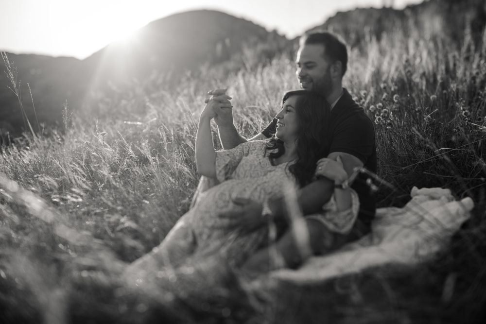 Intimate black and white photo of couple lounging on blanket in mountain meadow.
