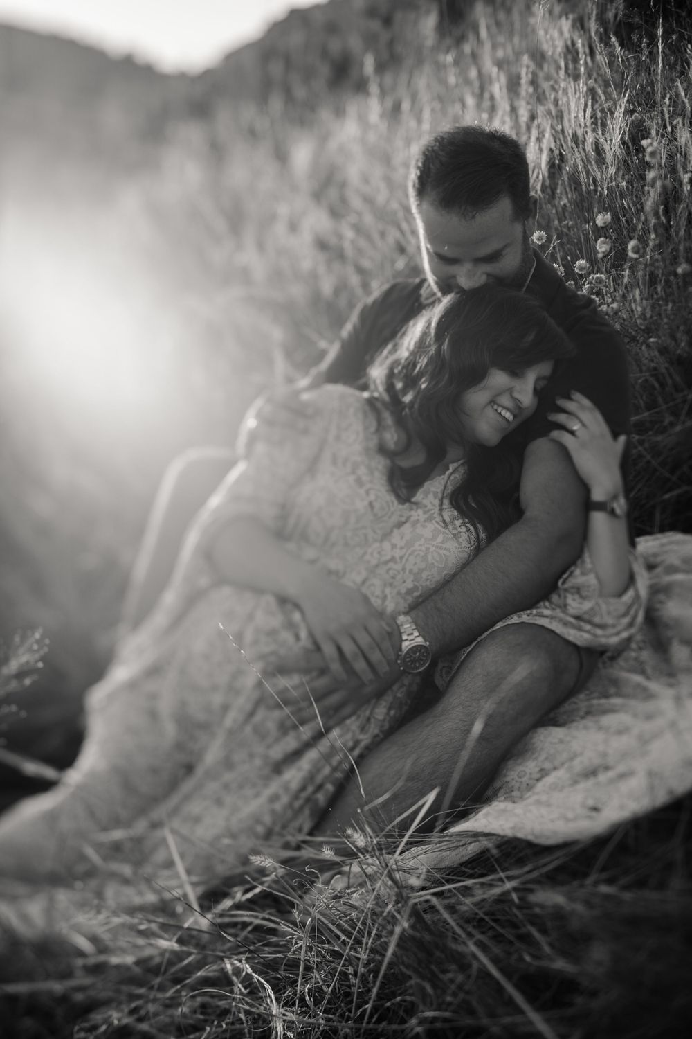 Intimate black and white moment captured of couple resting together in mountain grass.