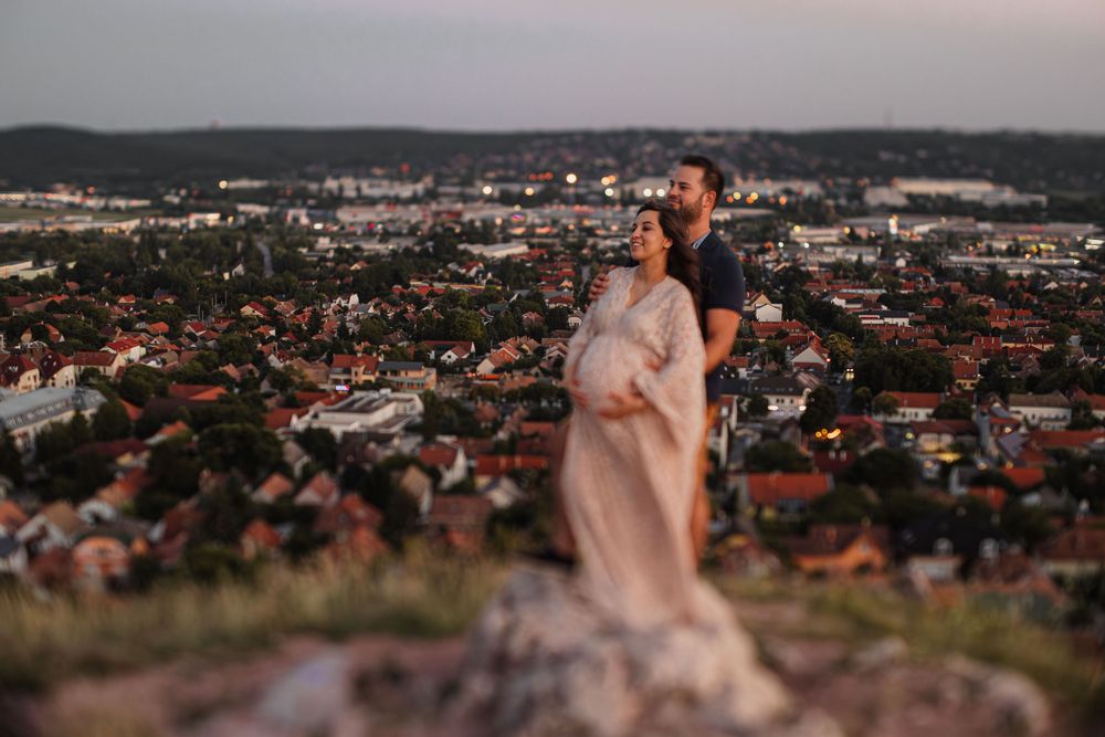 A couple shares an intimate moment overlooking a cityscape during golden hour.