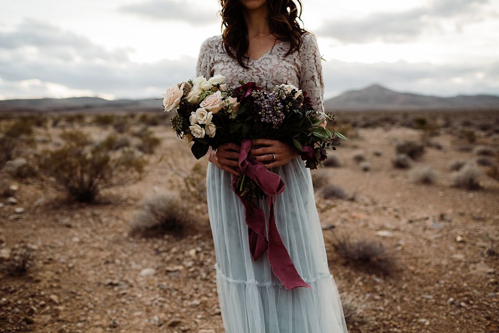 bride holding wedding bouquet in dirt field