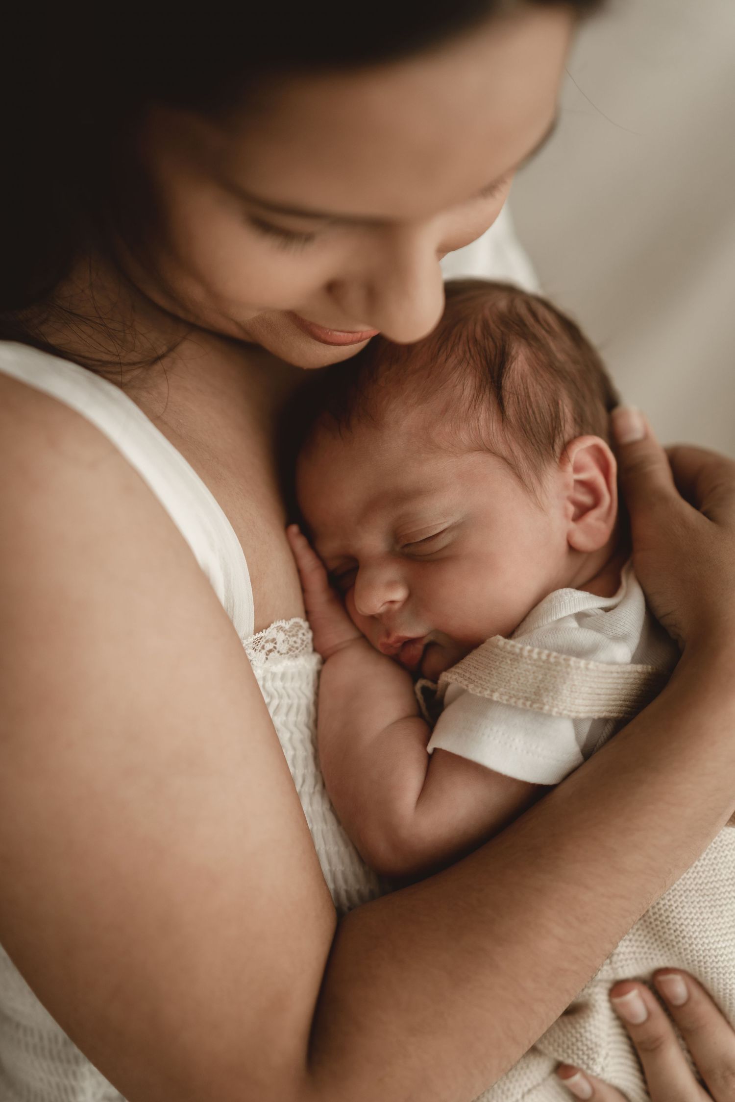 Close-up of tender moment between parent and sleeping newborn.